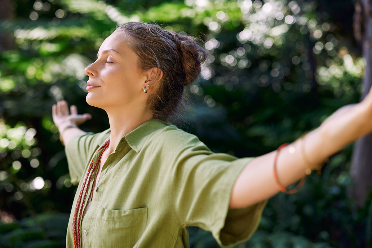 Foto einer Frau mit geschlossenen Augen und ausgebreiteten Armen