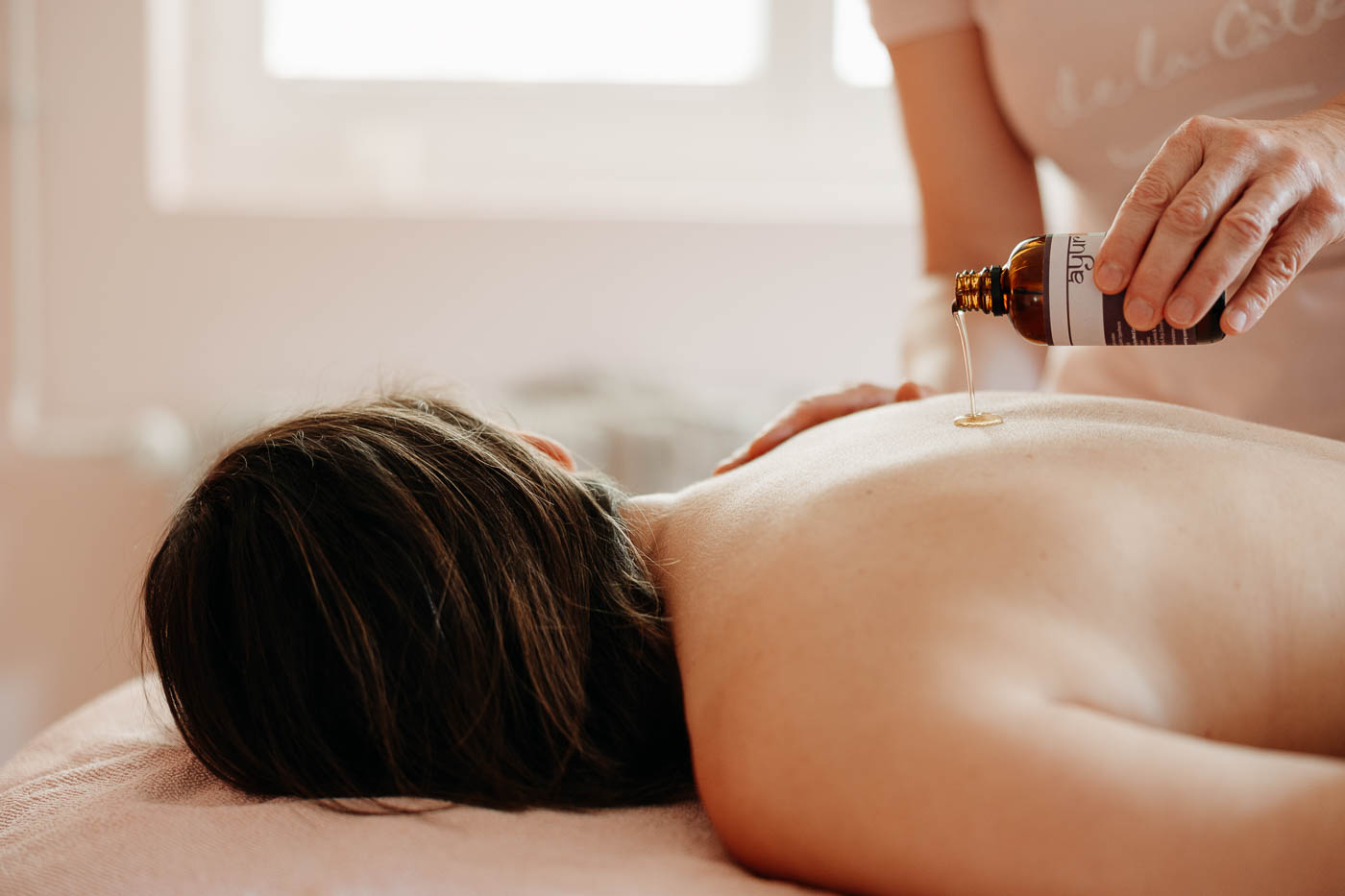 Öl fliesst aus der Flasche auf einen Rücken