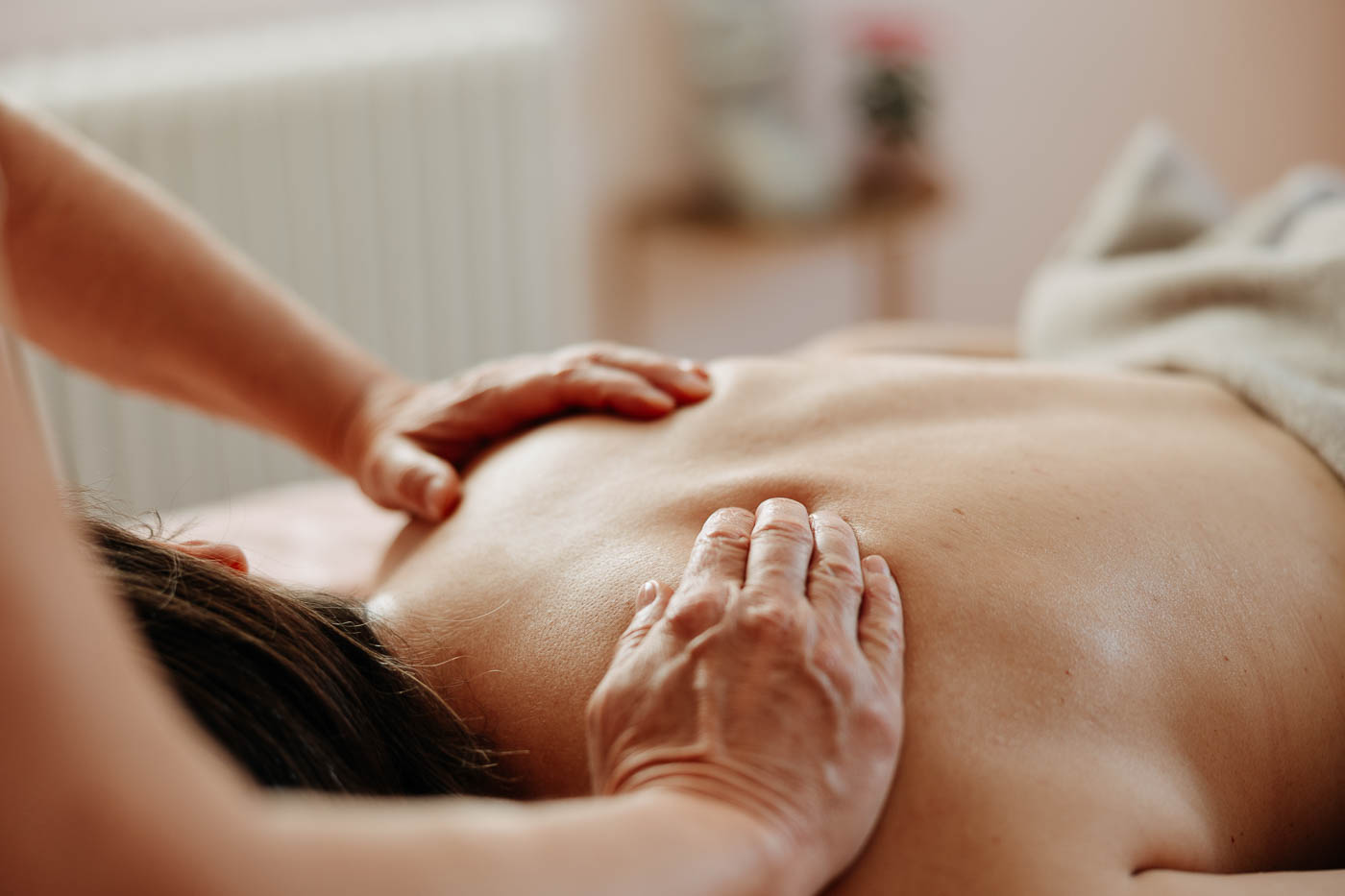 Zwei Hände liegen auf dem Rücken einer Frau für eine Massage